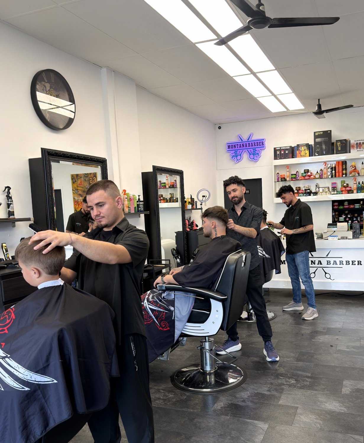 Drie barbiers aan het werk bij Montana Barber, klanten in de stoel
